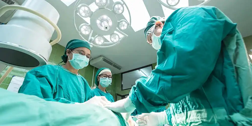 Team of surgeons in masks and scrubs performing surgery in a modern hospital operating room.